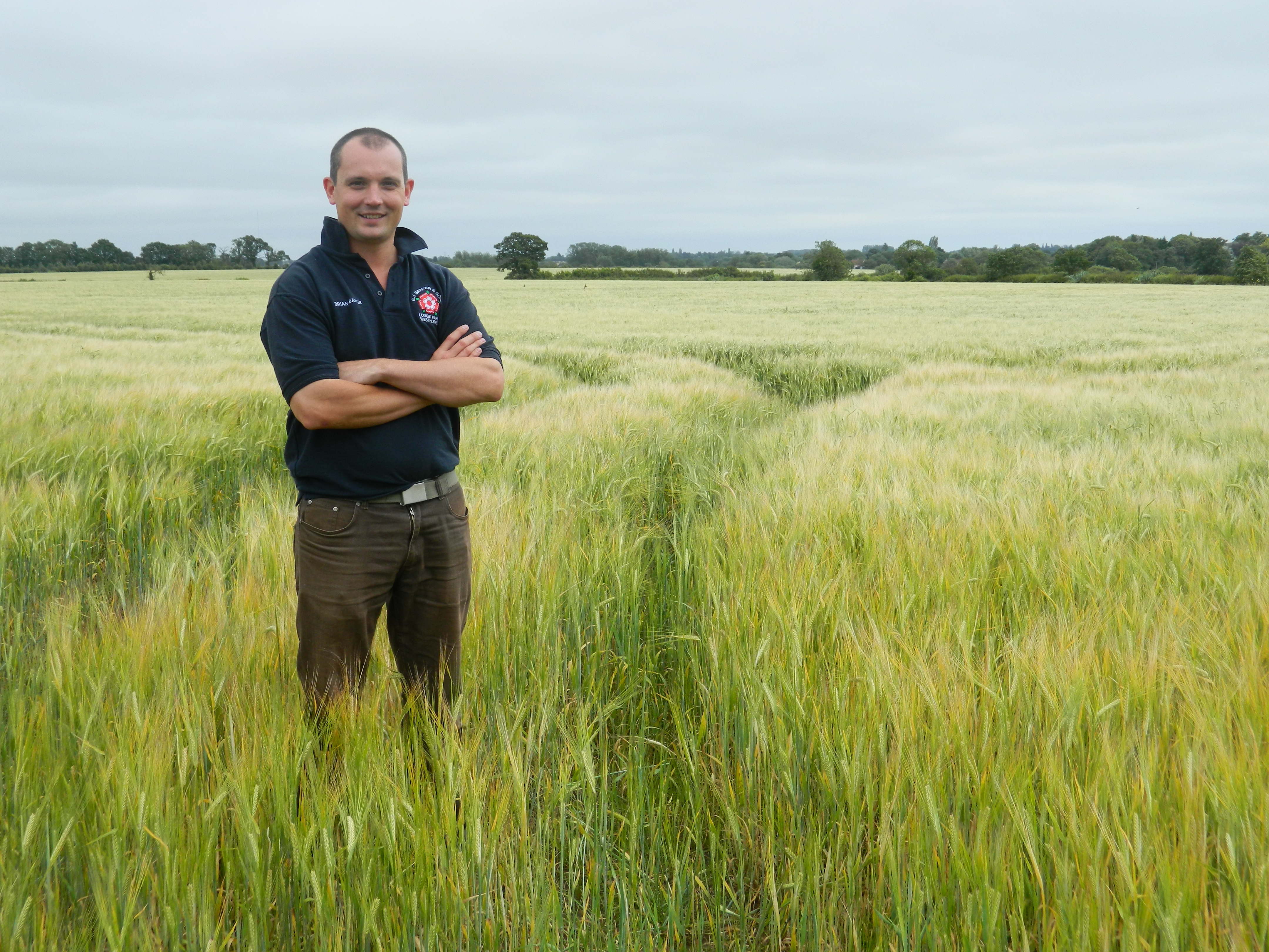 Brian Barker standing in a field of barley